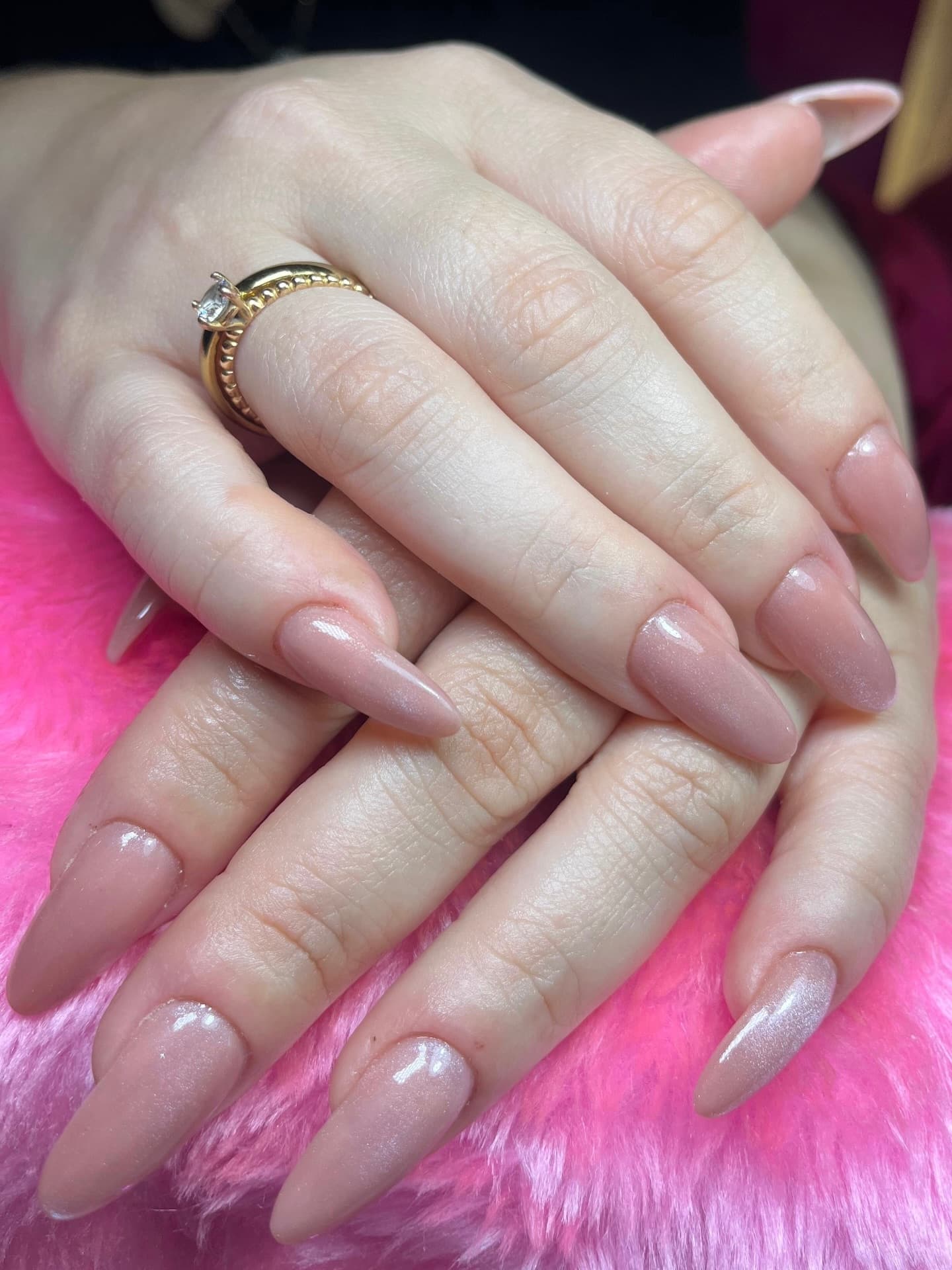 Uñas almendradas nude con shimmer sutil y argolla metálica en dedo medio