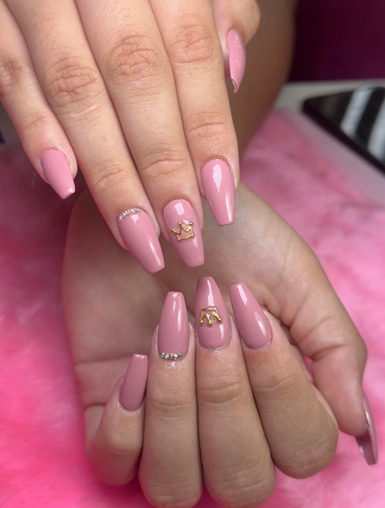 Uñas acrílicas rosadas con corona de joyas en uña acento central