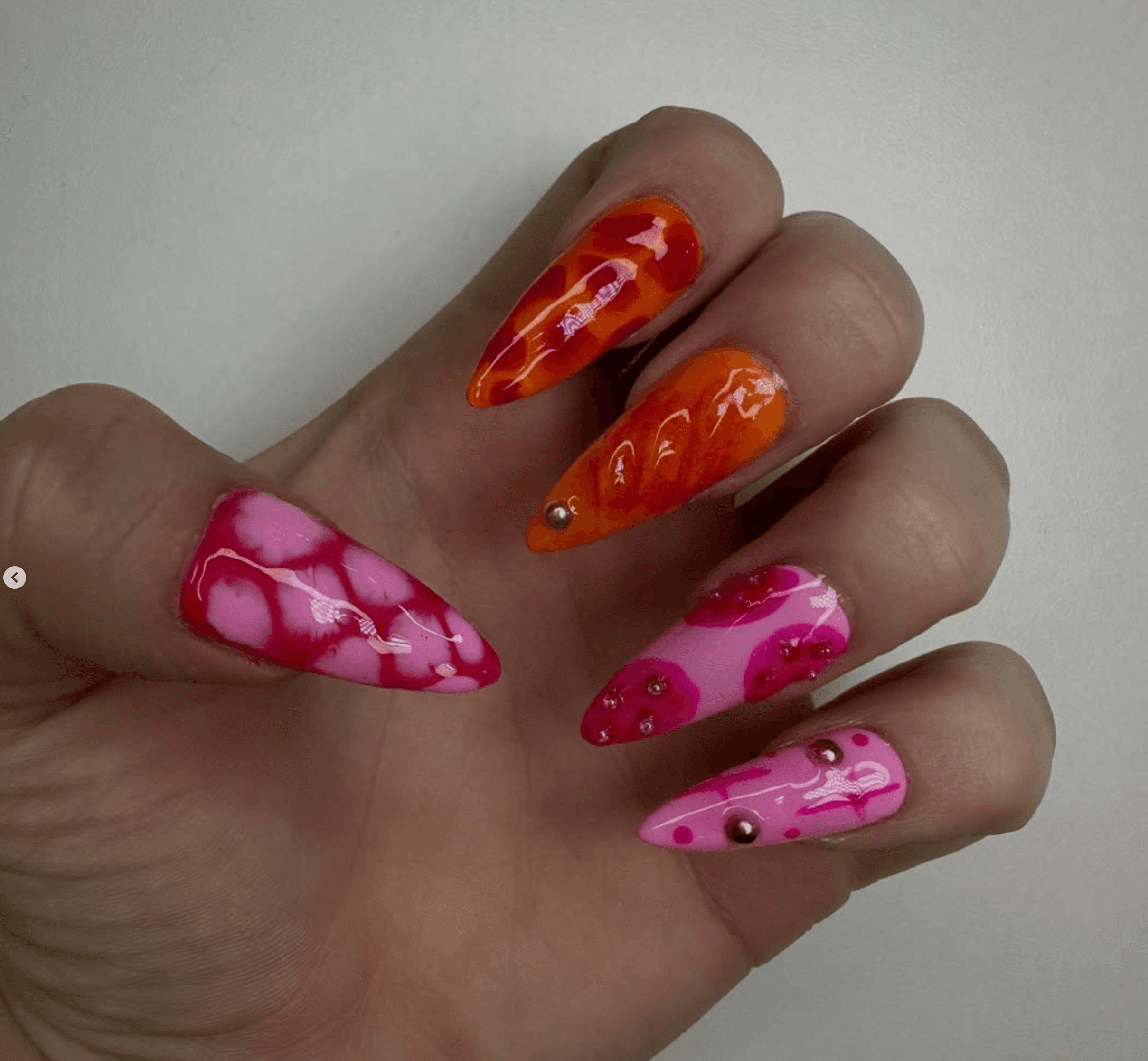 Uñas con arte abstracto en rosa y naranja con rhinestones de colores