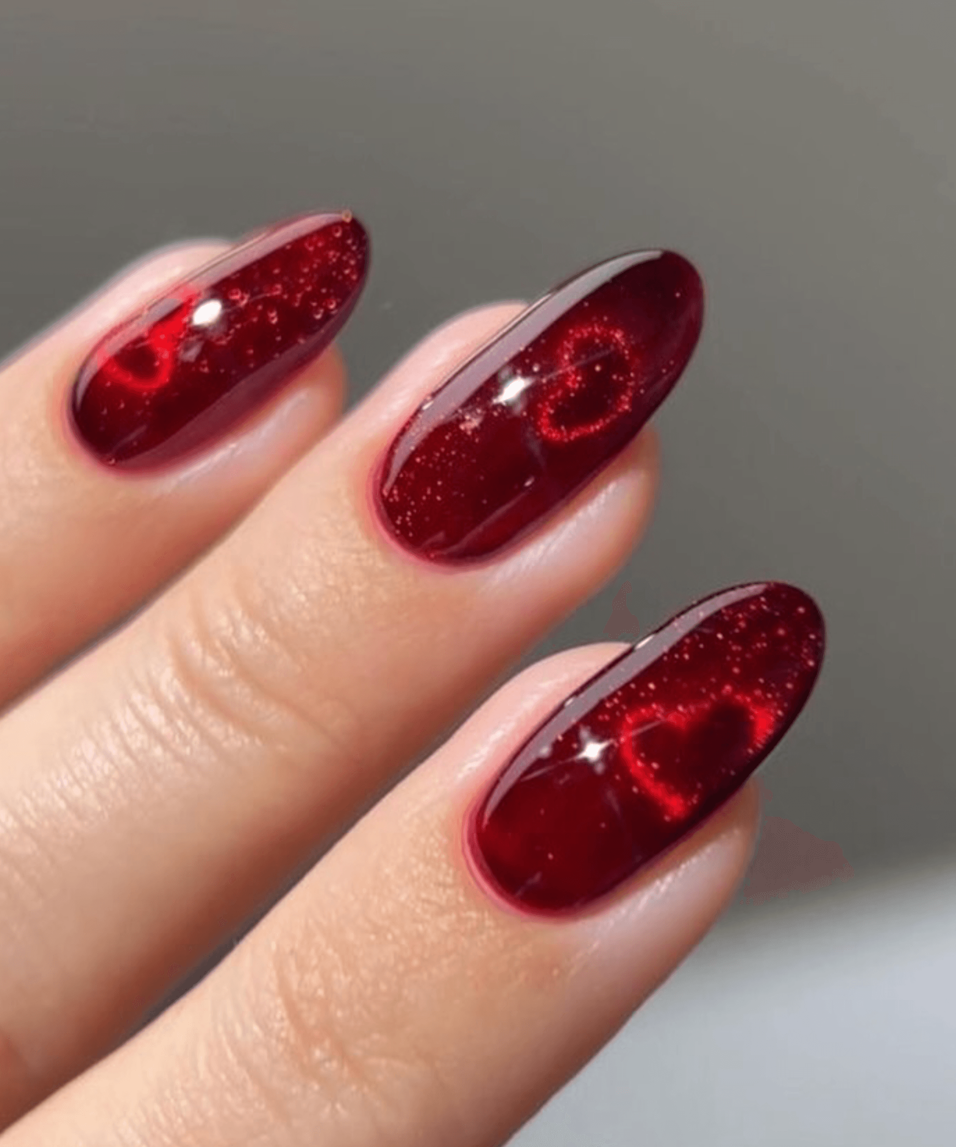 Uñas almendradas rojo con cat eye cromo y glitter fino en base
