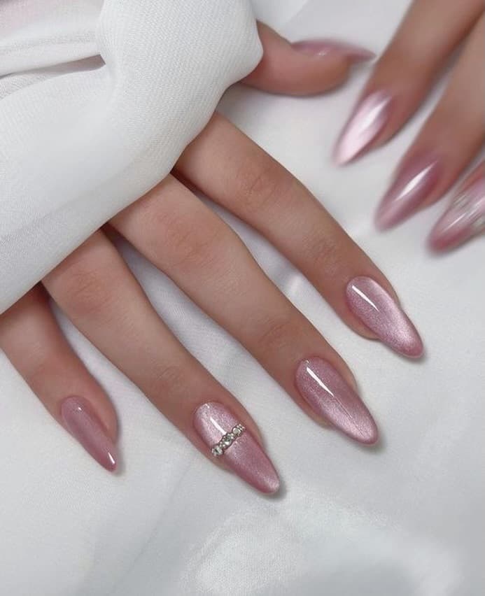 Pink cat-eye chrome nails with rhinestone detail at the tip of the accent nail